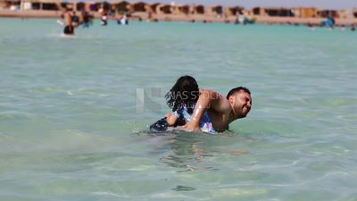 Little girl enjoying learning to swim with her father in the sea and fresh air