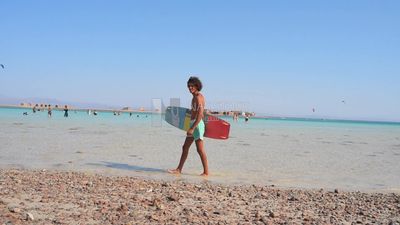 Young man in a swimsuit holds a surfboard ready to go water skiing