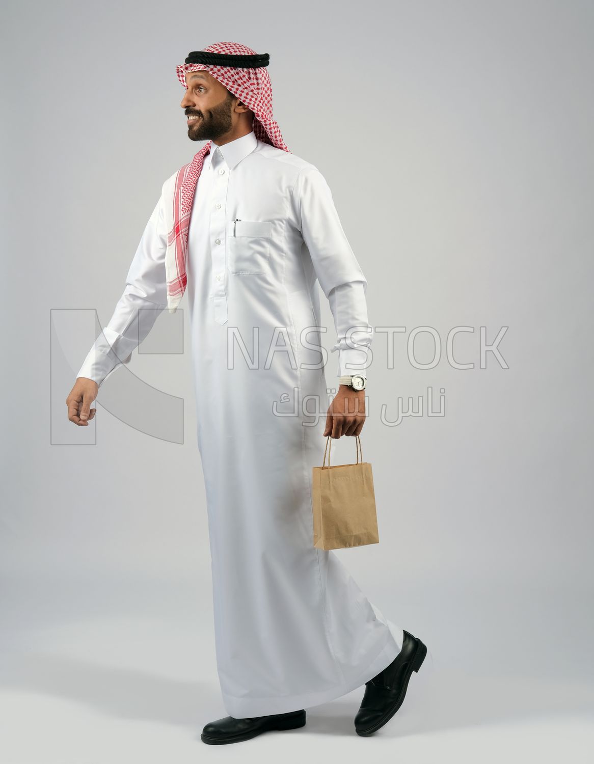 رجل خليجي يمسك بيده كيس من اكياس التسوق