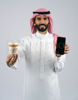 Gulf man holding a Mobile phone and coffee cup