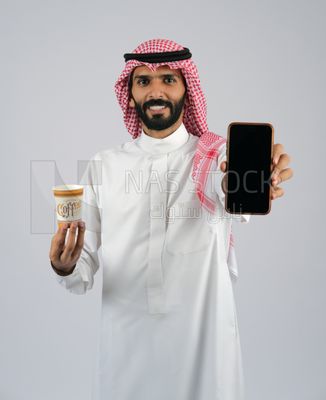 Gulf man holding a Mobile phone and coffee cup