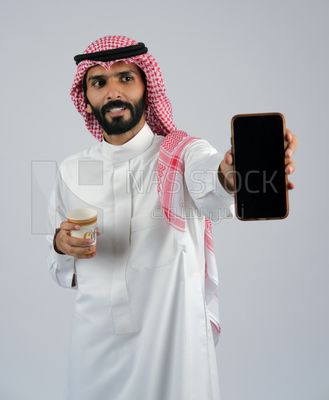 Gulf man holding a Mobile phone and coffee cup