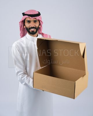 رجل  خليجي يرتدي الزى السعودى مع الشماغ و العقال يحمل صندوق كرتونى فارغ مفتوح , استلام طلبات الونلاين, التسوق الالكتروني, خدمة التوصيل , التسوق عبر برامج وتطبيقات الهاتف المحمول , شركات الشحن و التوصيل , خدمات توصيل البضائع