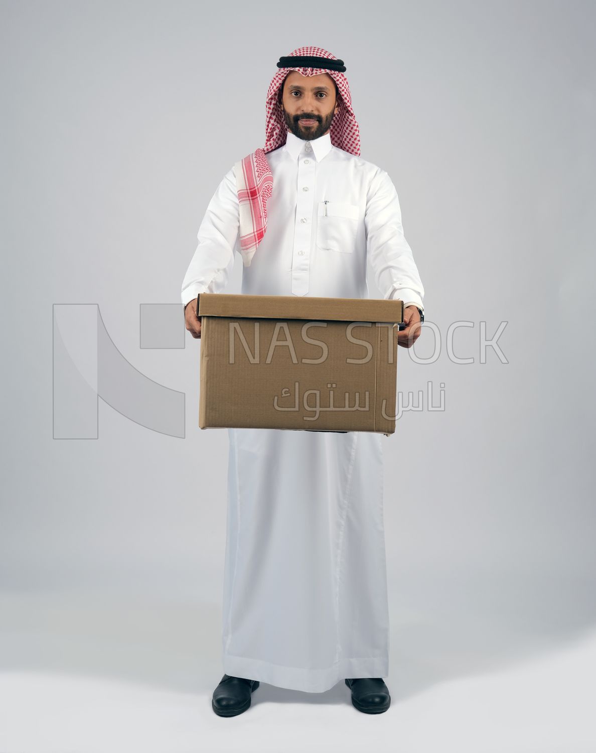رجل خليجي يرتدي الزي السعودي يحمل صندوق من الكرتون , يعمل في توصيل الطلبات , التسوق الالكتروني, طلبات اونلاين, عمليات الشحن والتوصيل , مندوب توصيل
