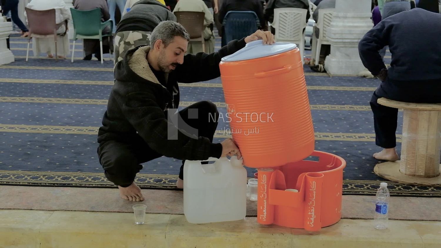 رجل يضع الماء من خزان الجليد في وعاء ، ويؤدي صلاة الفريضة في المسجد ، والعبادة والاقتراب من الله