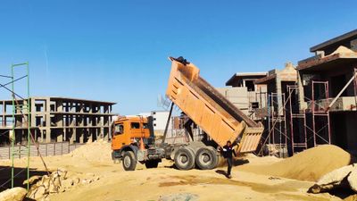 Dump truck unloads the load of sand used in construction work