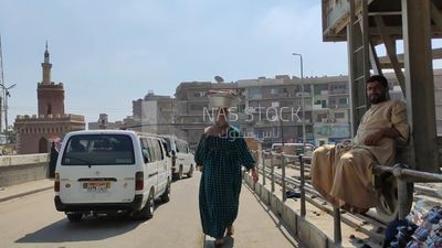 Egyptian woman carries a pot on her head and walks down the street, Egypt