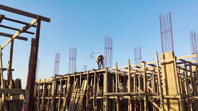 Worker on a construction site installing concrete poles