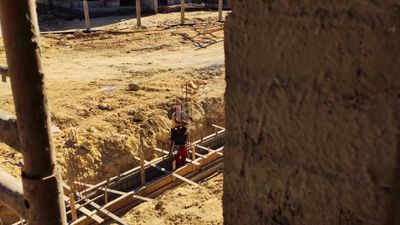 Workers at a construction site installing concrete columns and then pouring cement on them