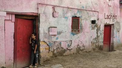 Child stands at the door of his house in a popular area in Egypt , boy standing in the street