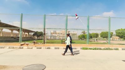 Two men are walking near a football field