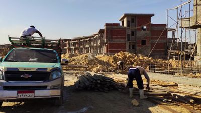 Workers unload a shipment of lumber into a construction site for use