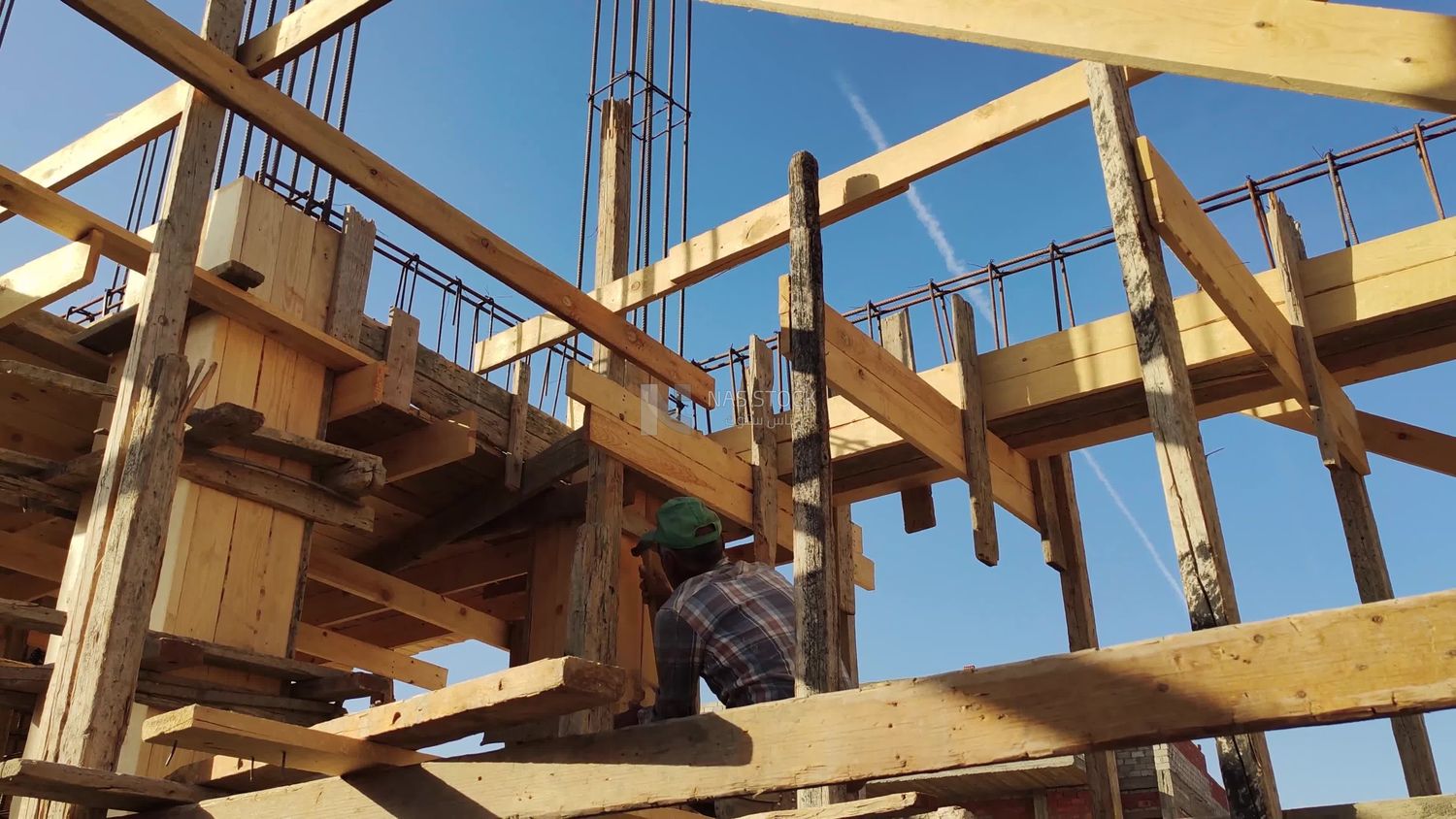 Worker installs wooden planks to form a wooden structure into which cement is poured