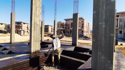 Worker paints a fence brown at a construction site