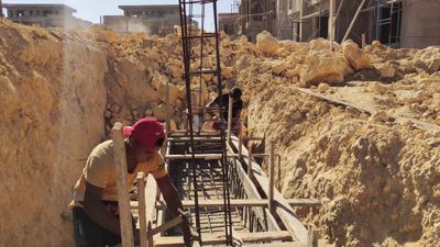 Workers constructing the wooden structure inside which concrete is being poured
