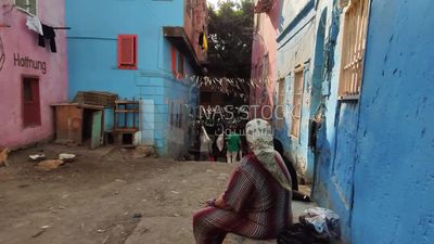 Woman sits in front of her house in a street in one of the popular areas in Egypt