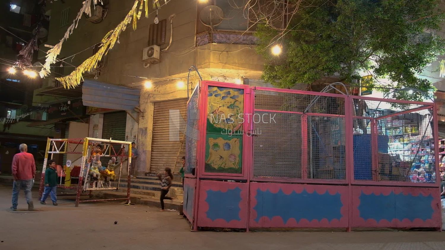 Boy sitting on the swing in the street, Ramadan nights