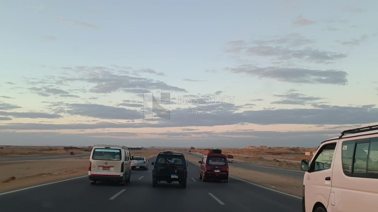 Video from inside a car traveling quickly on the desert road with a stunning sunset view