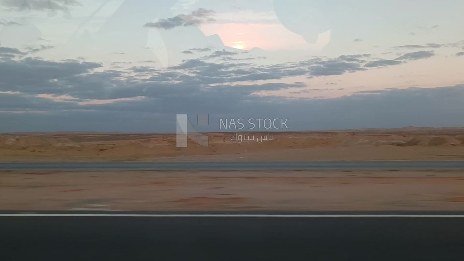 Video showing a camera inside a car traveling on a desert road with a stunning view of the sky