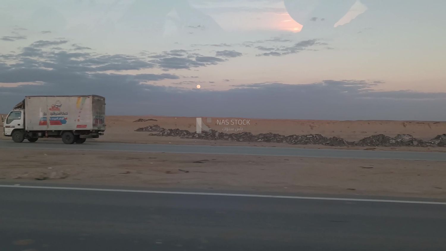 Video showing a camera inside a car traveling on a desert road with a stunning view of the sky