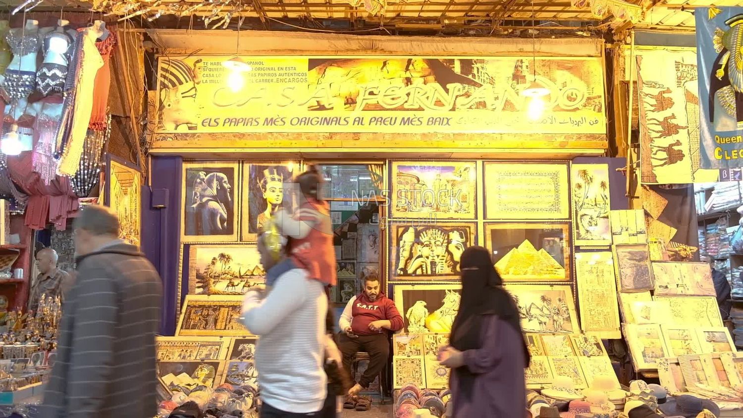 Man sitting in front of a store for Different Egyptian souvenirs for sale in a street shop, street, work