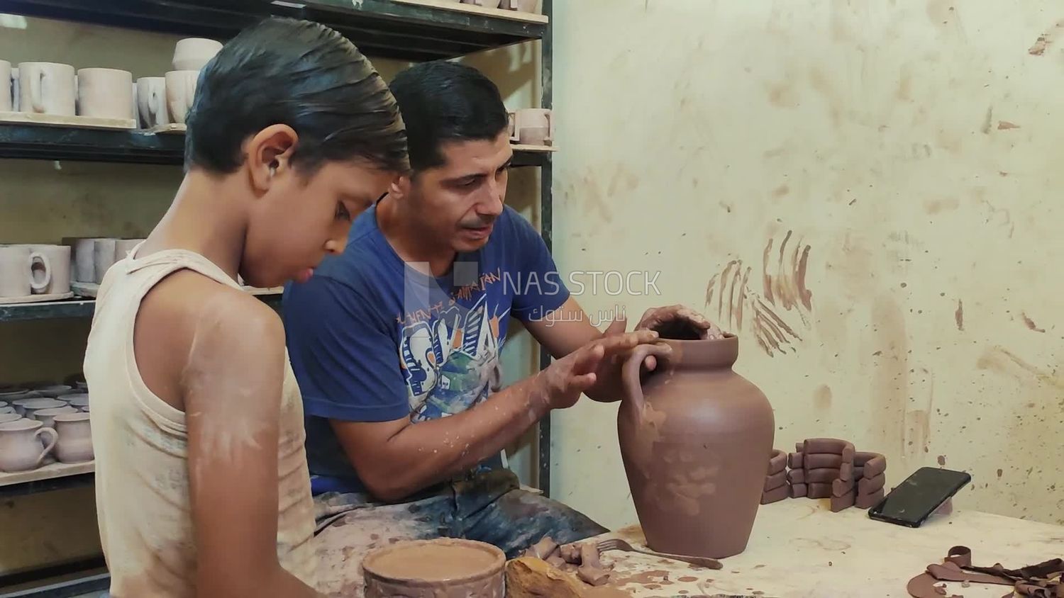 Man with his son working in a pottery workshop