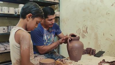 Man with his son working in a pottery workshop