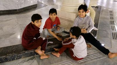 Boys playing cards in the mosque, watching the mobile, praying on the prayer rug, performing the obligatory prayer in the mosque, worship and draw close to God