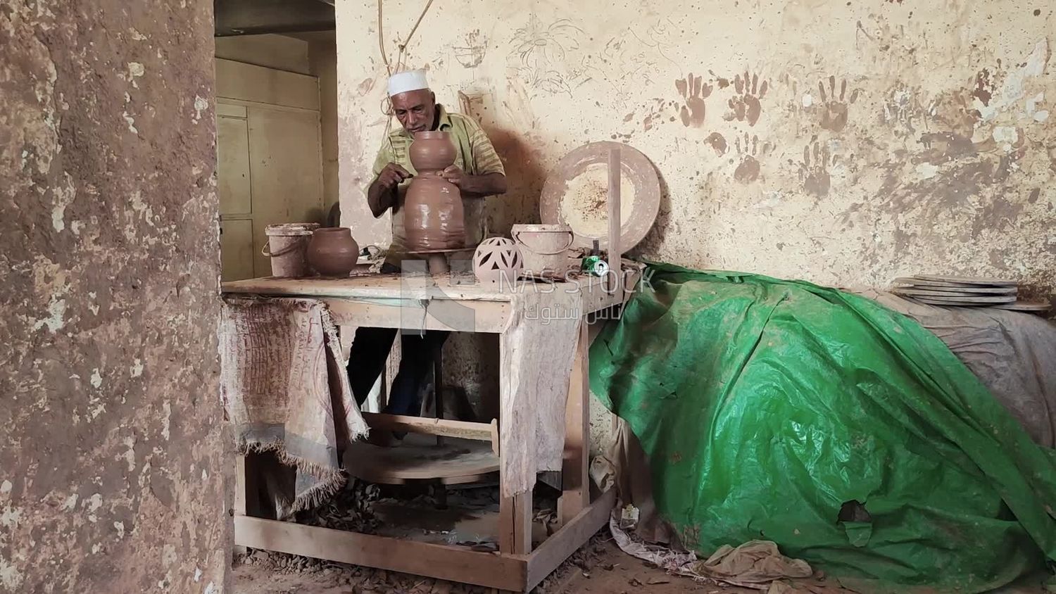 Old man working in a pottery workshop