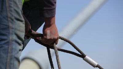 يحاول عاملان وضع الصلب على حبل من أسلاك الفولاذ ، والعمل ، والبناء ، والأدوات والمعدات الهندسية