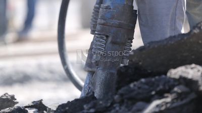 Worker using a drill to make a hole in the ground