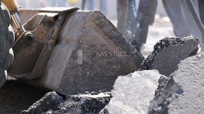 Tractor lifts a stone from the ground on a building site, engineering tools and equipment