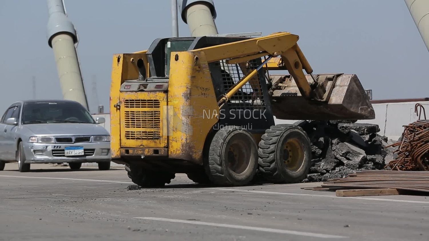 Tractor lifts a stone from the ground on a building site, engineering tools and equipment