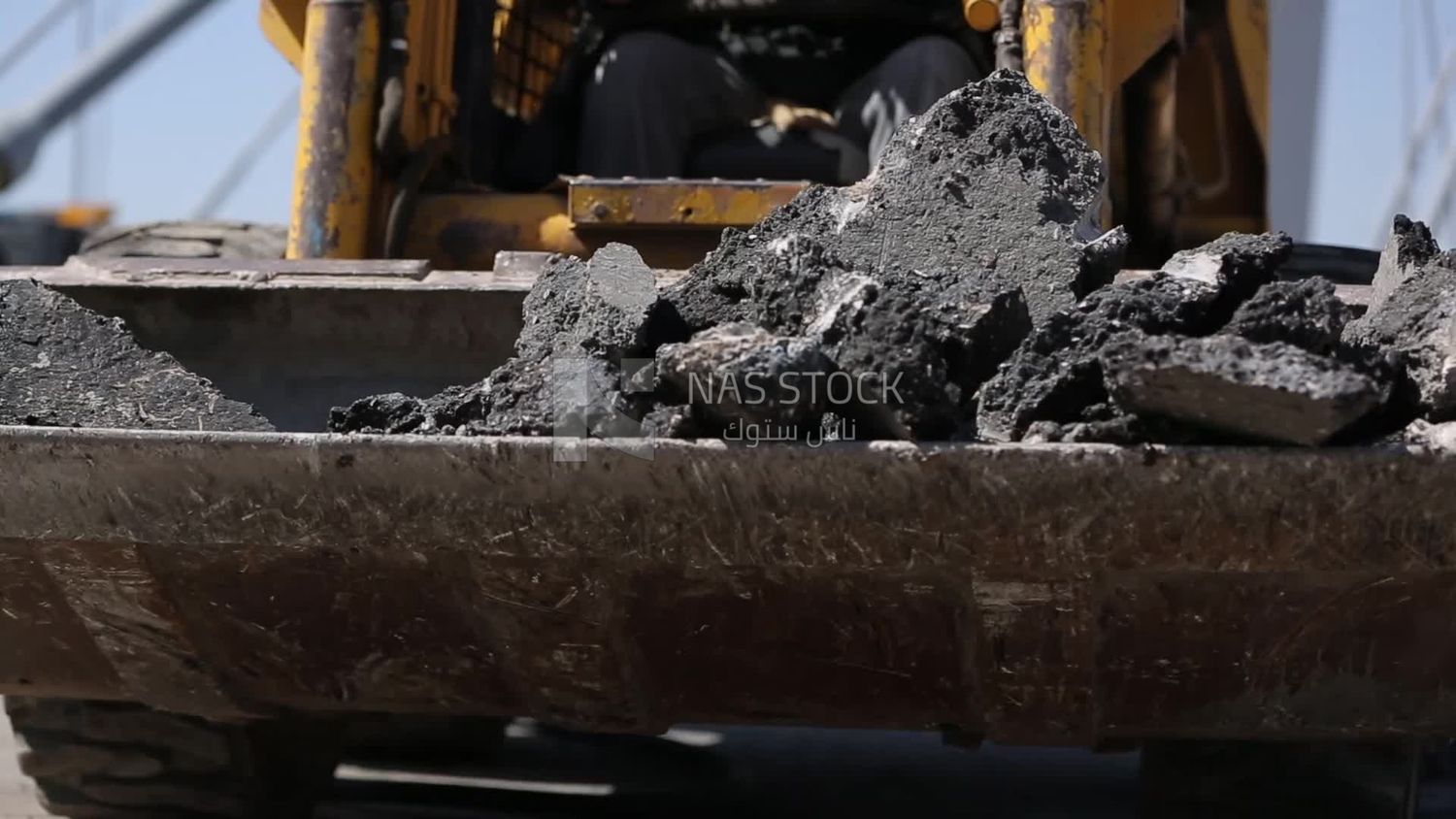 Tractor lifts a stone from the ground on a building site, engineering tools and equipment