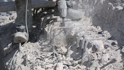 Worker using a drill to make a hole in the ground