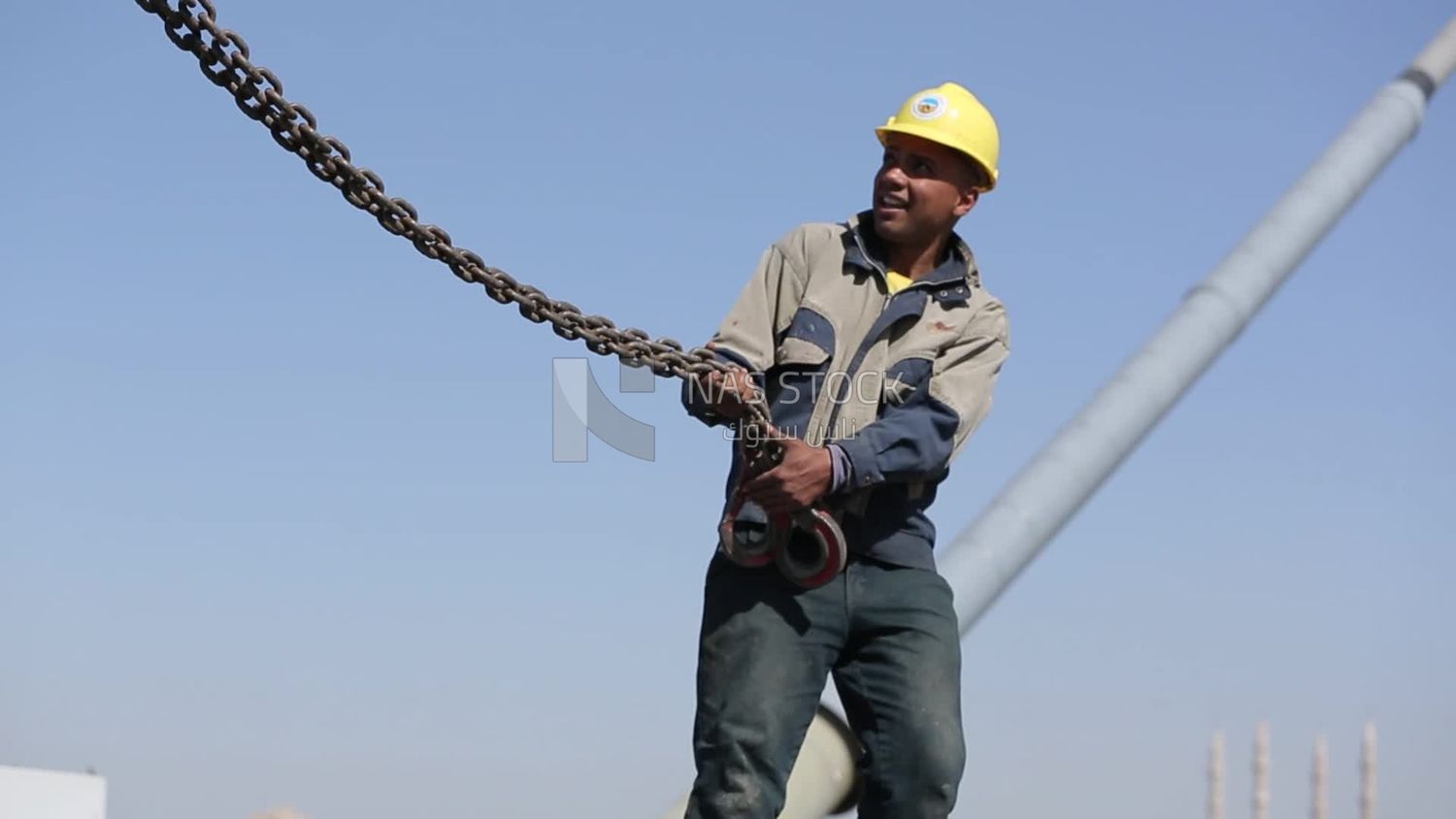 يحاول عاملان وضع الصلب على حبل من أسلاك الفولاذ ، والعمل ، والبناء ، والأدوات والمعدات الهندسية