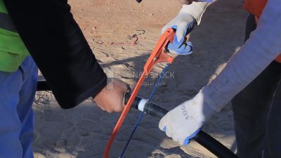 Two men are cutting a pipe in a site of solar energy