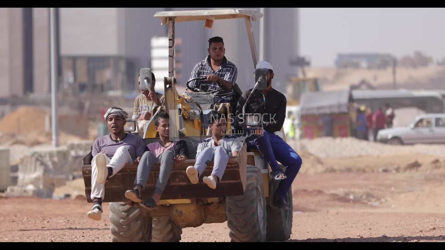 Man driving a loader tractor, and people sitting in it