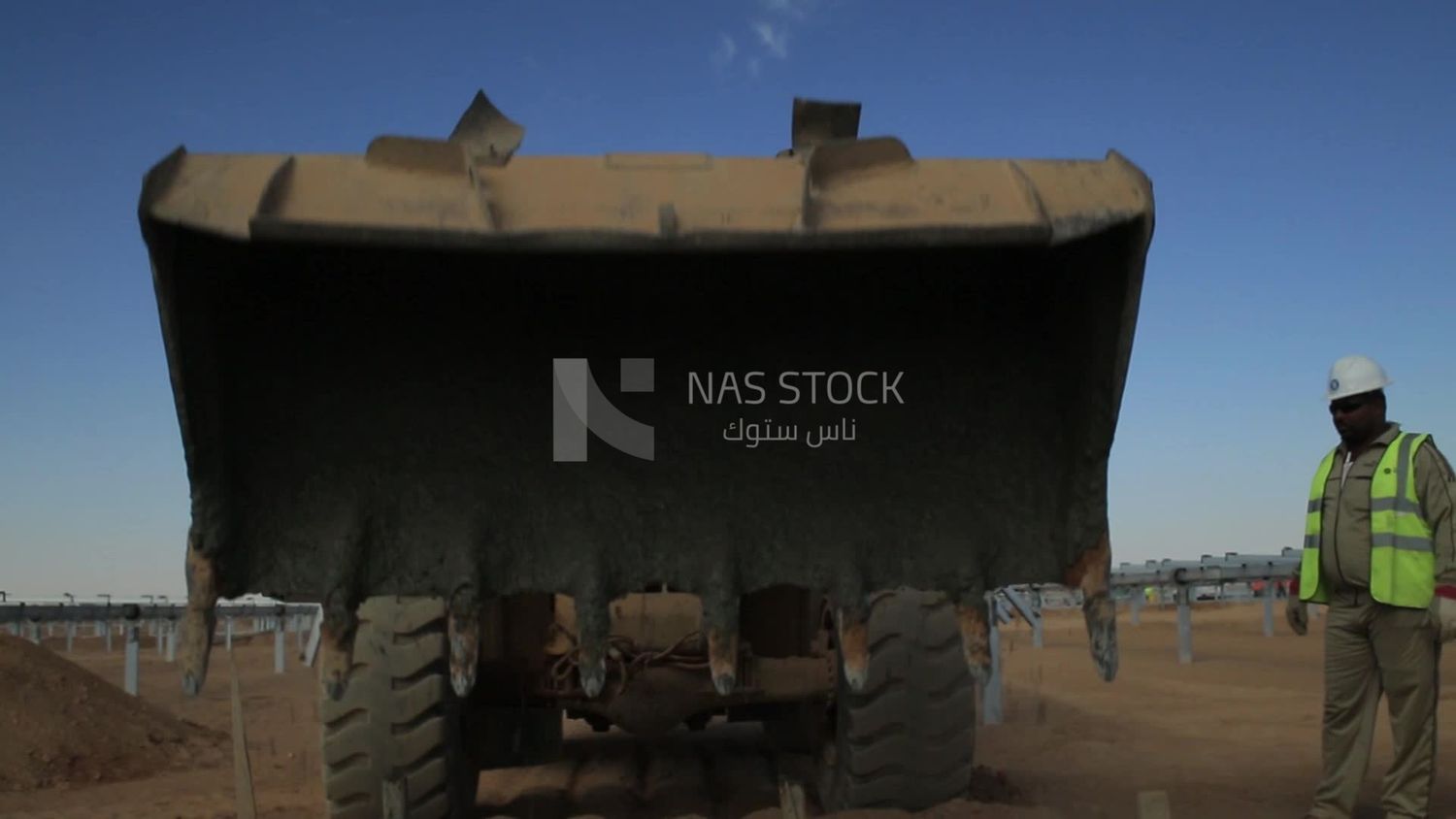 Man driving an excavator throws cement in a hole in solar energy