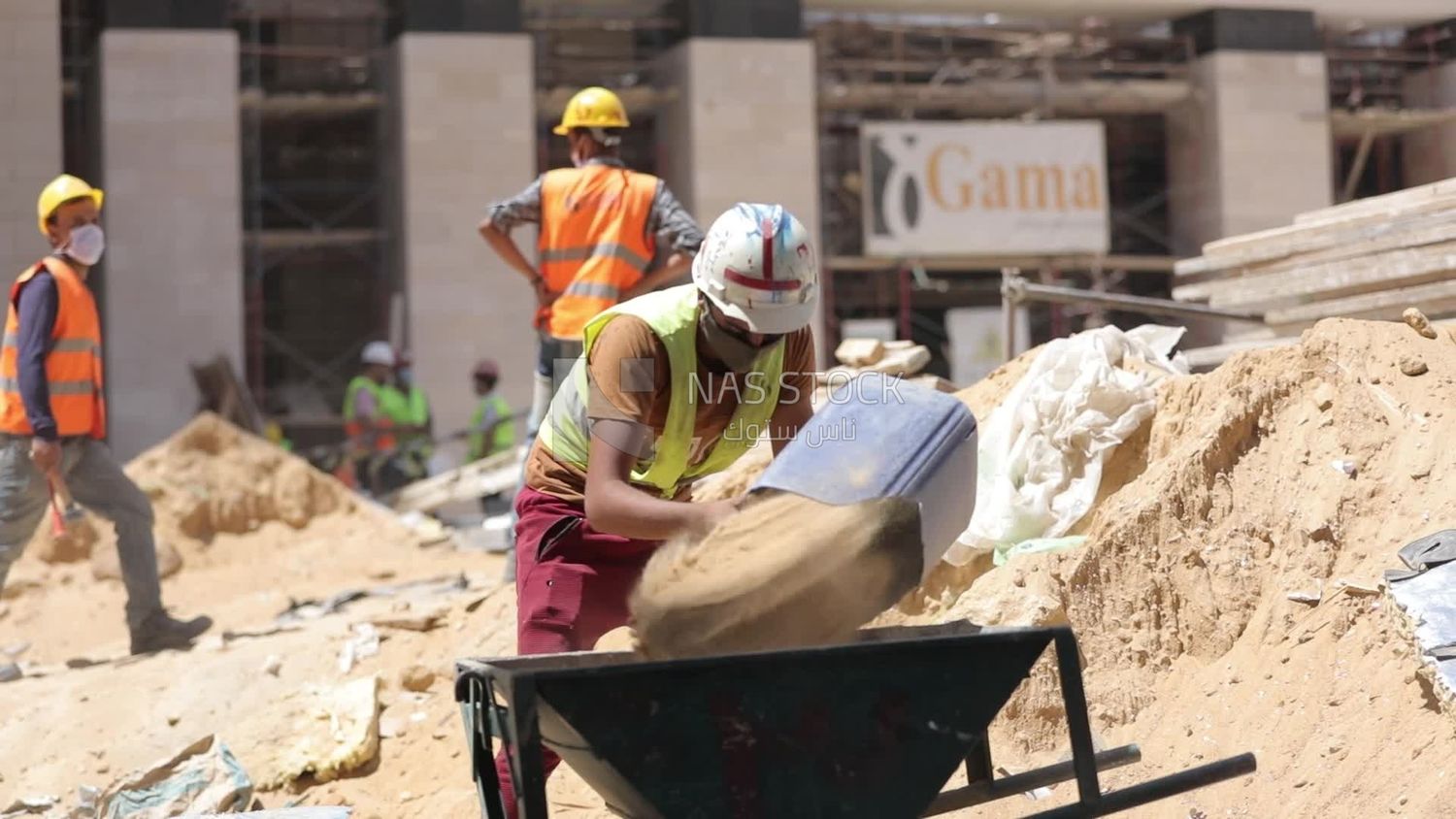 Worker puts sand on the cart at a building site