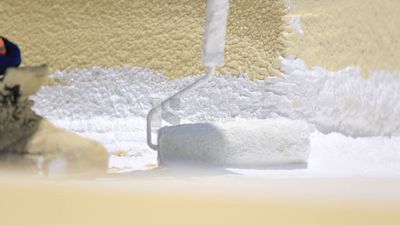 Worker applies material insulating the building using the paint roller, Isolation work