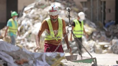 Worker puts bricks on a cart at a building site