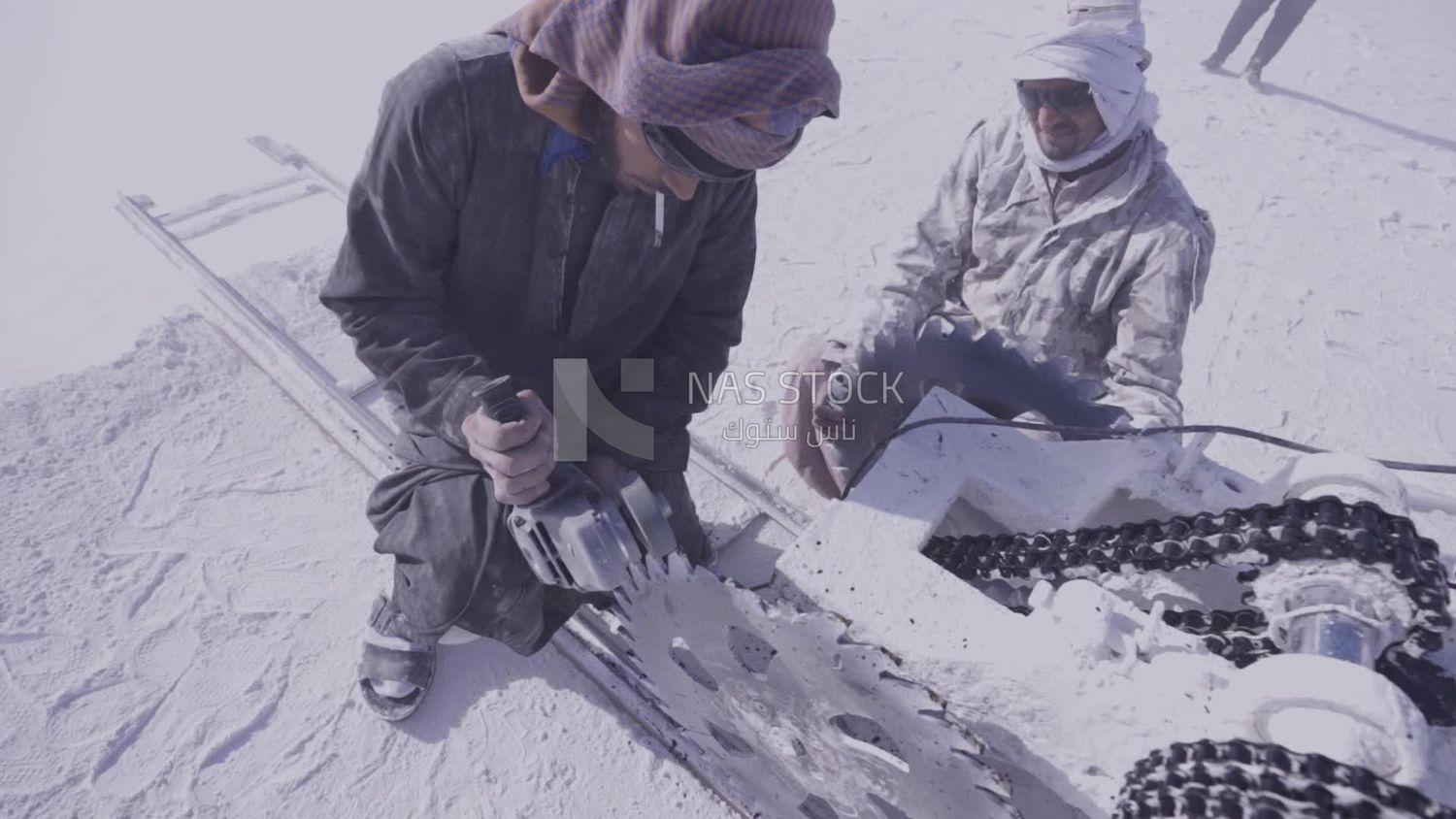 Two men try to fix the machine in the quarry
