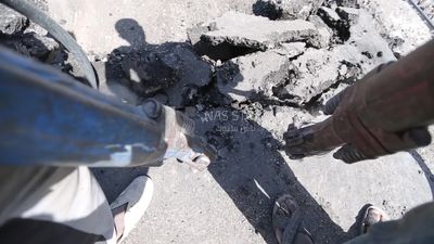 Worker using a drill to make a hole in the ground
