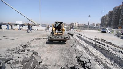 Tractor lifts a stone from the ground on a building site, engineering tools and equipment