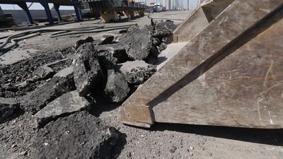 Tractor lifts a stone from the ground on a building site, engineering tools and equipment