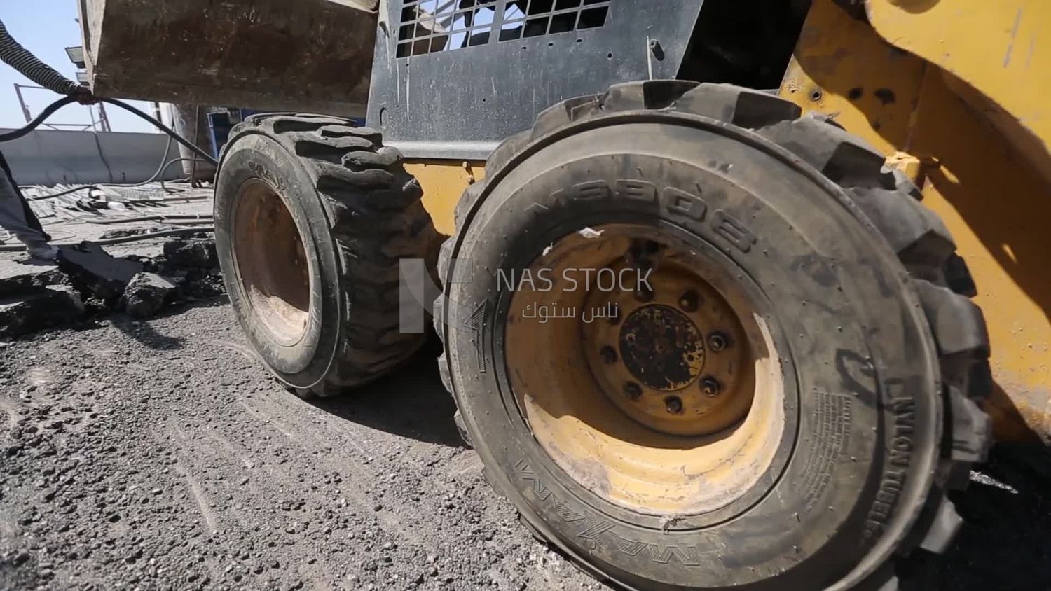 Tractor lifts a stone from the ground on a building site, engineering tools and equipment
