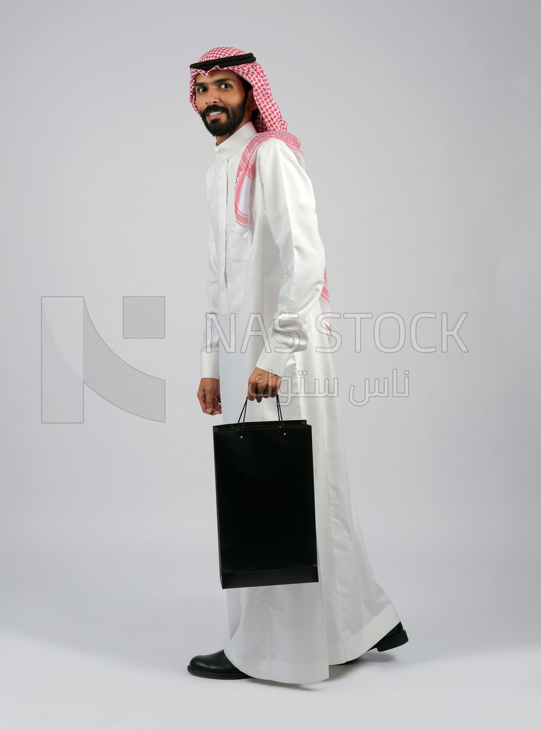 Gulf man carrying black shopping bag