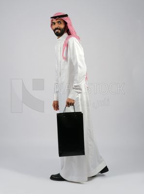 Gulf man carrying black shopping bag