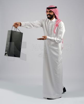 Gulf man carrying black shopping bag